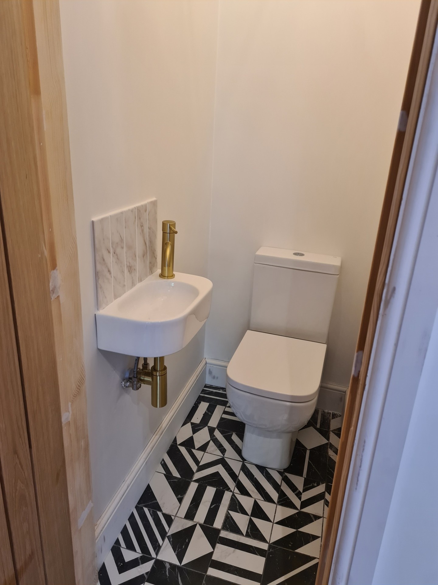 Completed cloakroom with toilet, wall-hung basin and geometric floor tiles