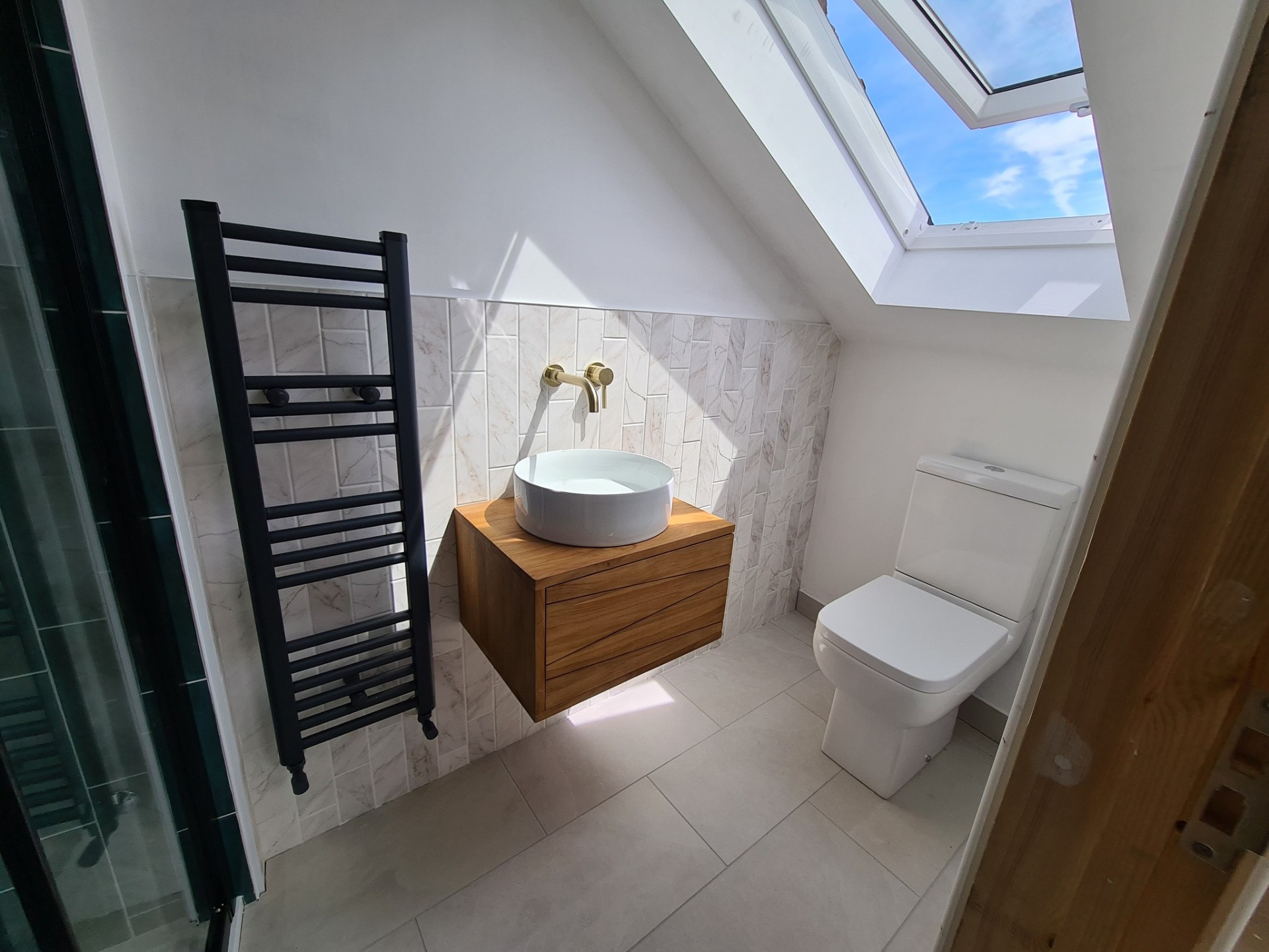 Loft conversion bathroom with oak vanity, vessel basin, towel radiator and skylight