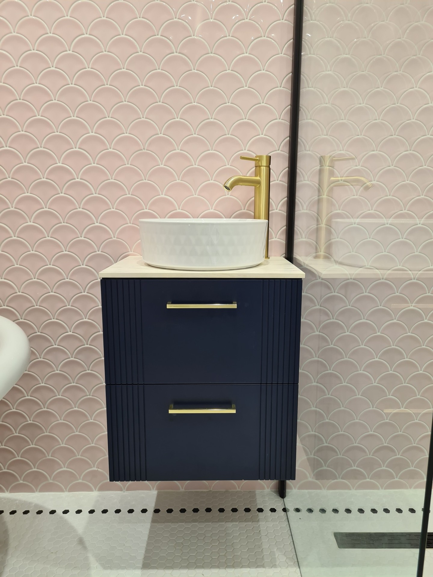 Navy vanity unit installed with pink tile surround in modern bathroom