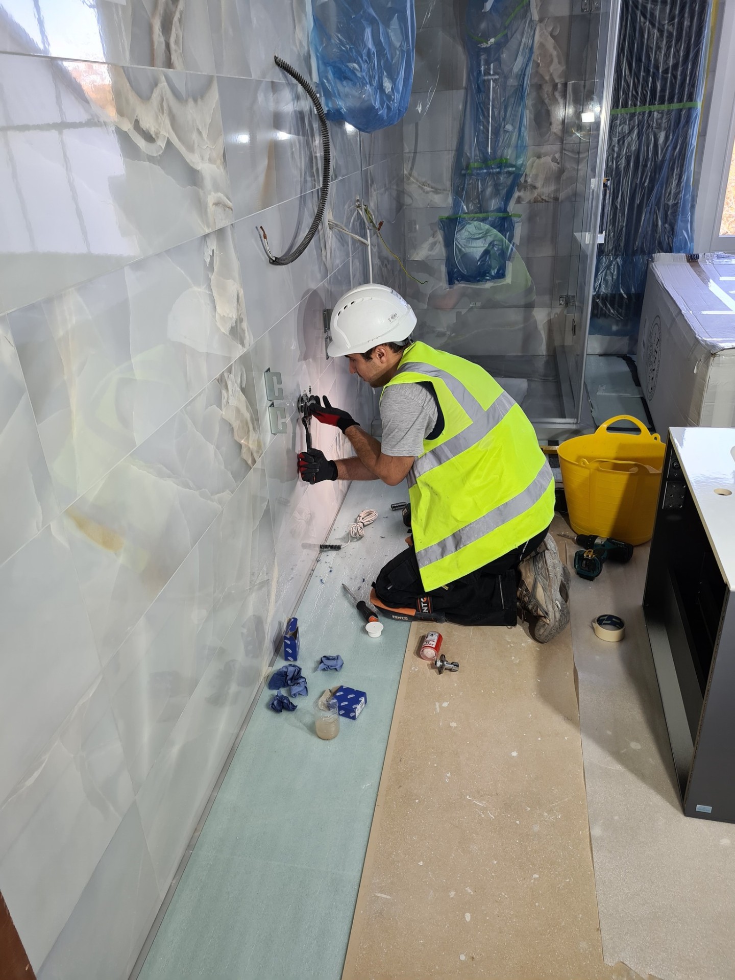 Engineer installing bathroom wall fittings on marble-tiled surface
