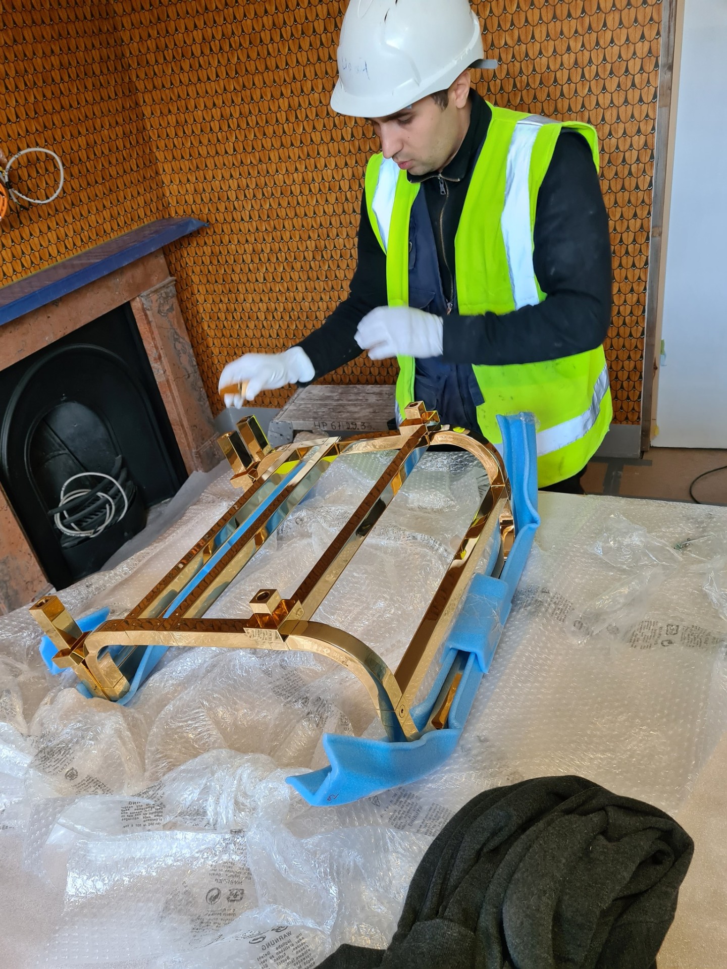 Plumber unpacking new brass column radiator from packaging