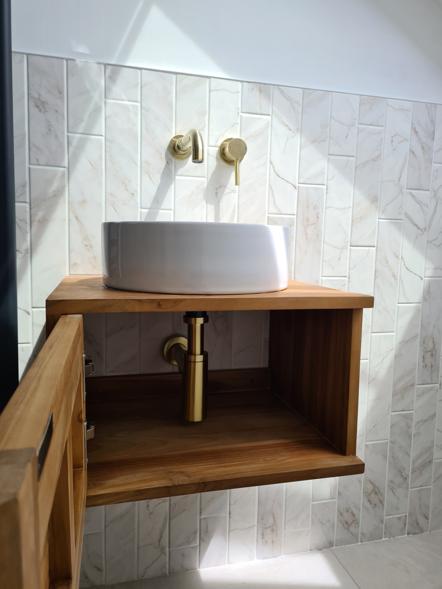 Vessel basin with gold bottle trap on timber vanity unit