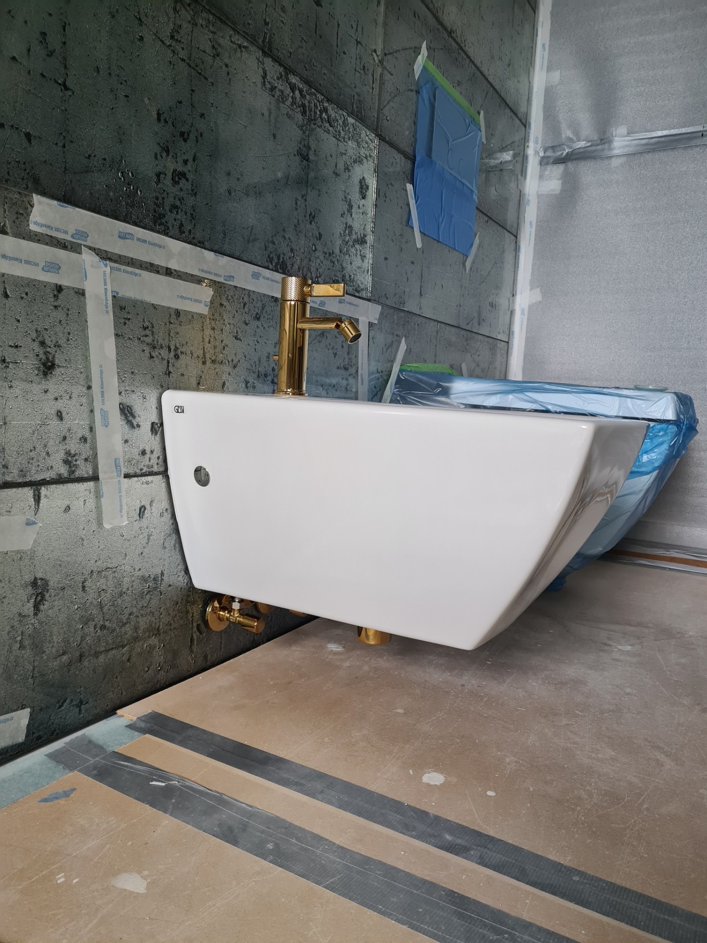 Wall-hung basin with gold tall tap during installation